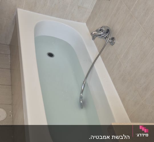 אמבטיה עם מים, ברז ומדף מתכת על קיר אריחים
